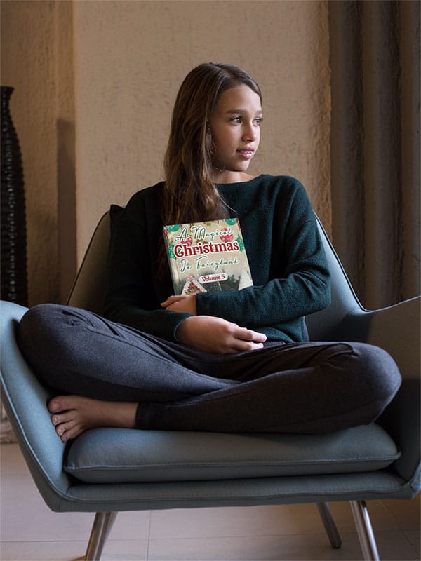 little-girl-holding-a-book-mockup-sitting-on-an-armchair-a19077