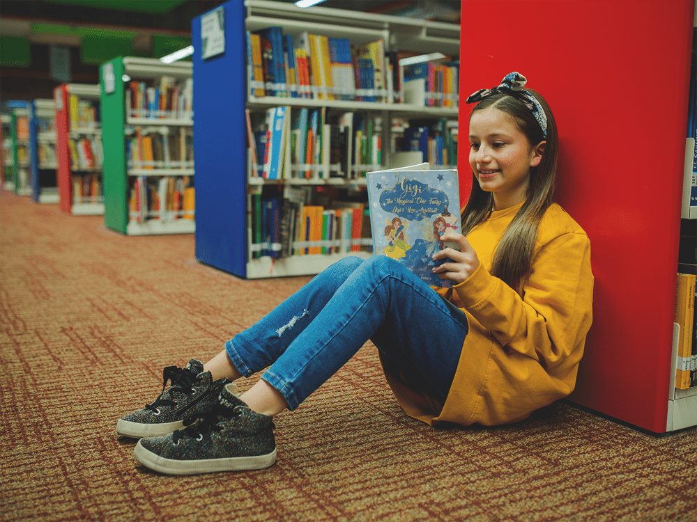 girl-with-a-yellow-sweater-reading-a-book-mockup-sitting-at-the-library-a19278-(1)-min