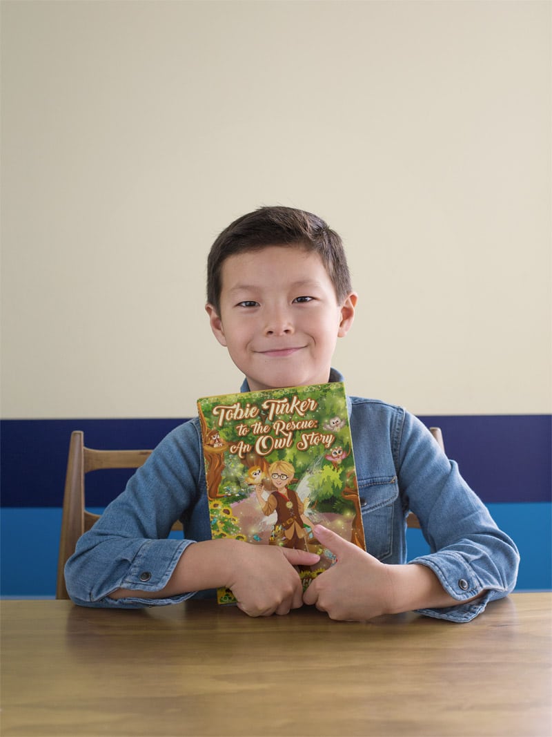book-mockup-featuring-a-child-sitting-on-a-wooden-table-23721